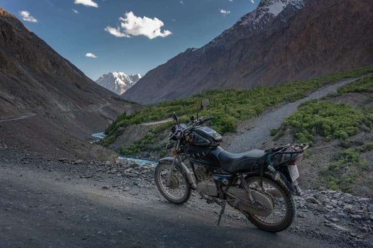 motorbike parked in steep valley with view of snow topped mountains in Pakistan