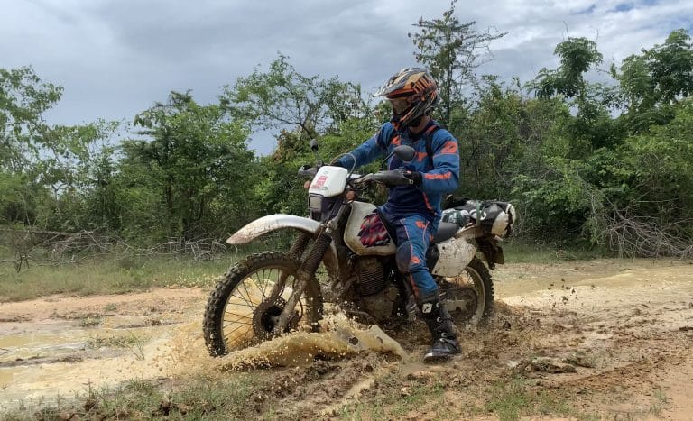 rider getting muddy on dirt trail on motorbike tour in Cambodia